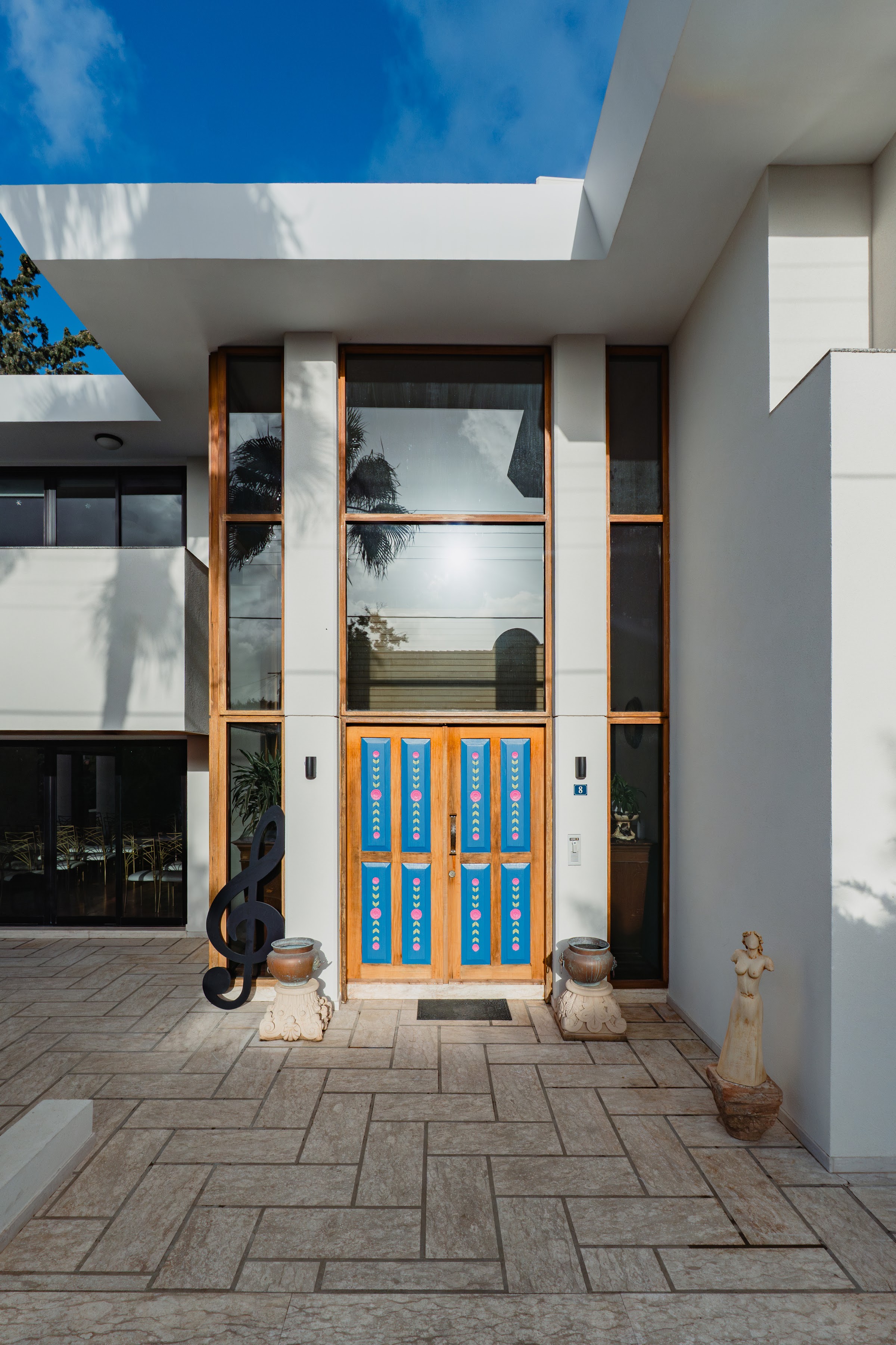 Programme venue exterior: modern white building with ornate blue doors and treble clef sculpture, Limassol, Cyprus