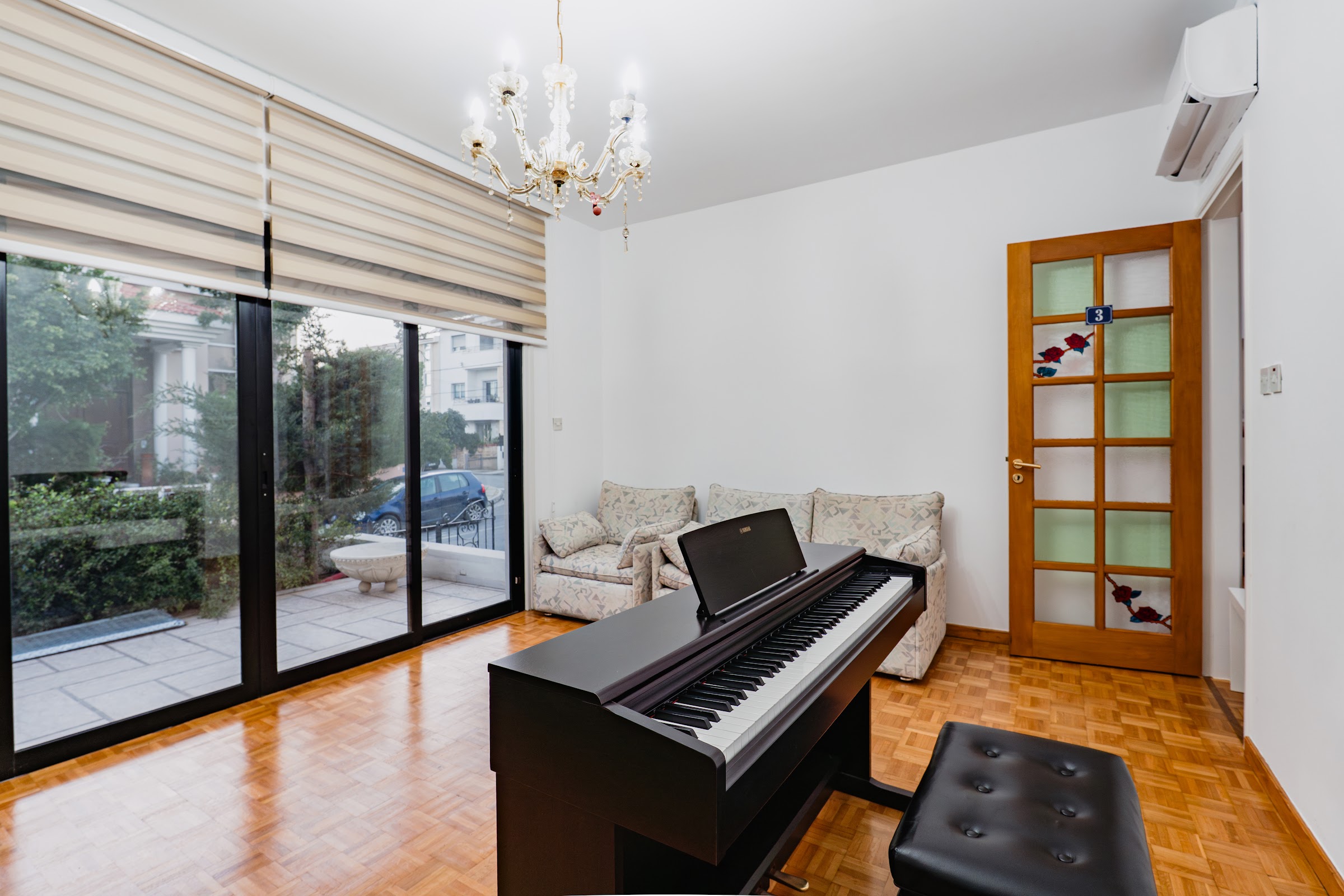 Bright practice room: digital piano by floor-to-ceiling windows overlooking Mediterranean greenery