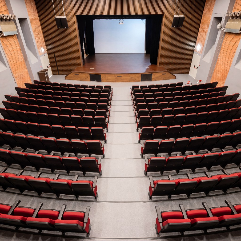 Laniteio Theatre from the balcony: bird's-eye view of the auditorium, wooden stage, curtains drawn, professional sound system